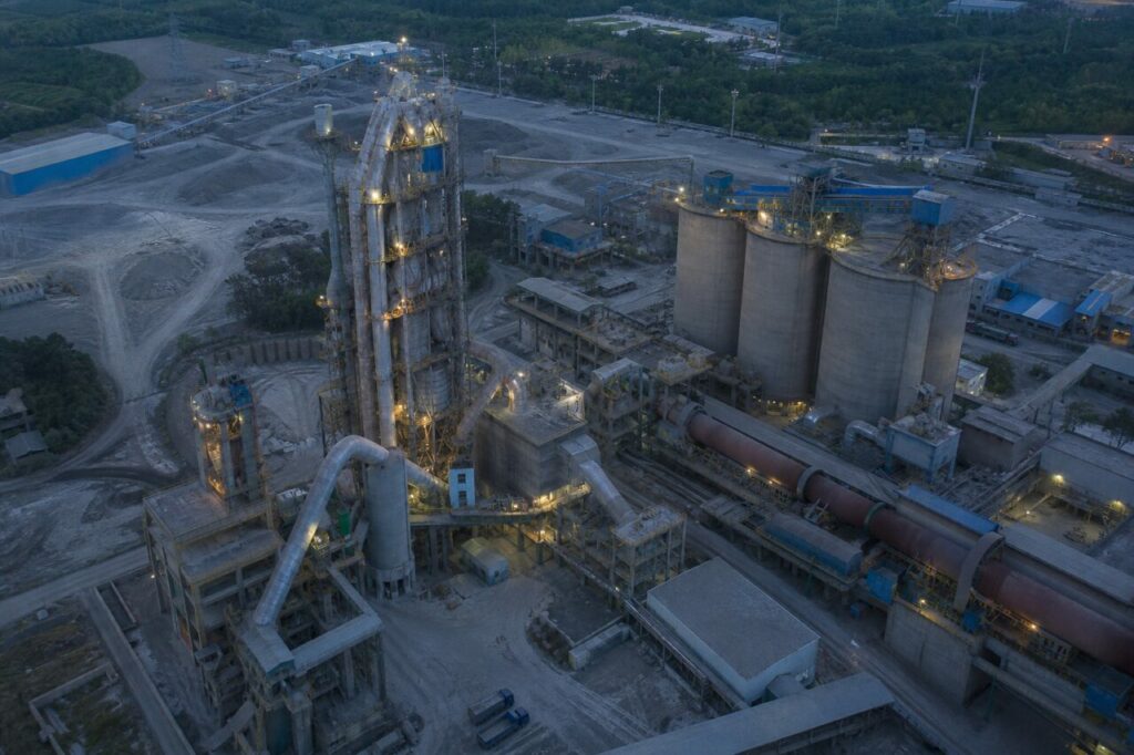 Met licht stof op wegen en installatiestructuren — Cementfabriek met draaitrommeloven en silo’s