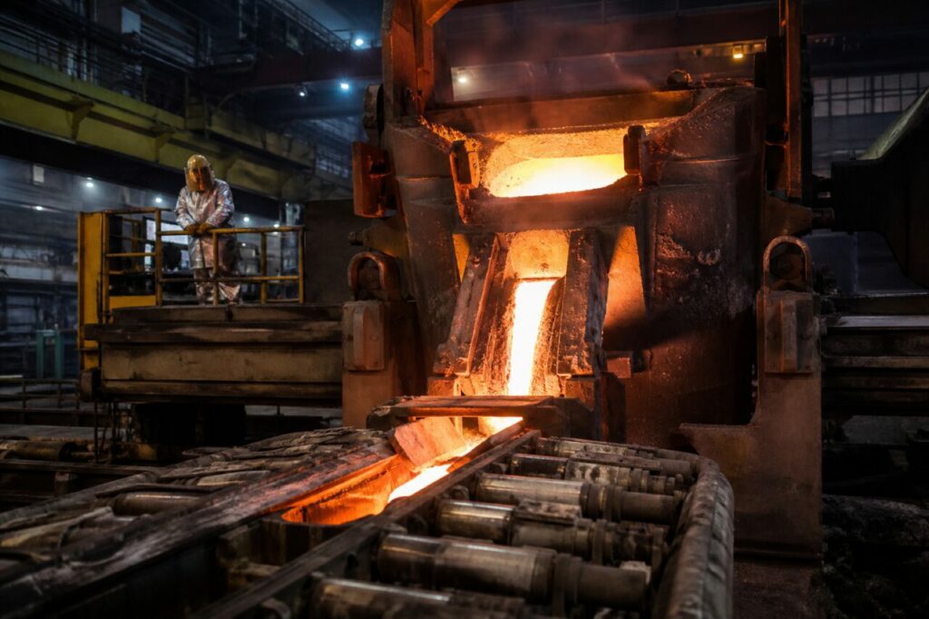 Colata continua di acciaio fuso sui rulli in una scura hall industriale siderurgica