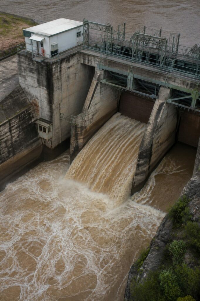 Coursier de crue canalisant l'eau brune entre les piles