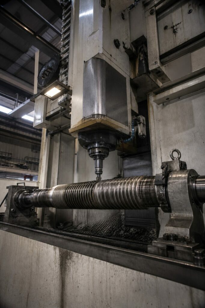 CNC-draadfreesmachine bewerkt de schroef van een hydraulische cilinder, laag standpunt in de werkplaats