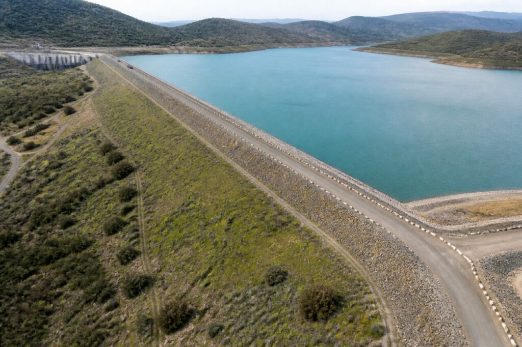 Retenue bordant le long barrage en remblai dans le relief ouvert