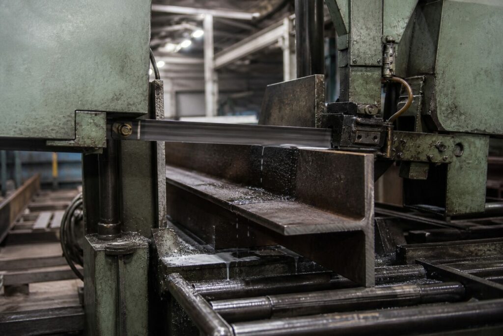 Scie à ruban industrielle CNC débitant une poutrelle d’acier — détail d’usinage