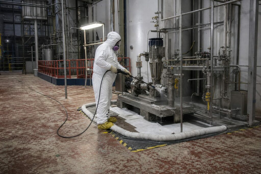Stainless pump skid receives cleaning around flanges and pump casing