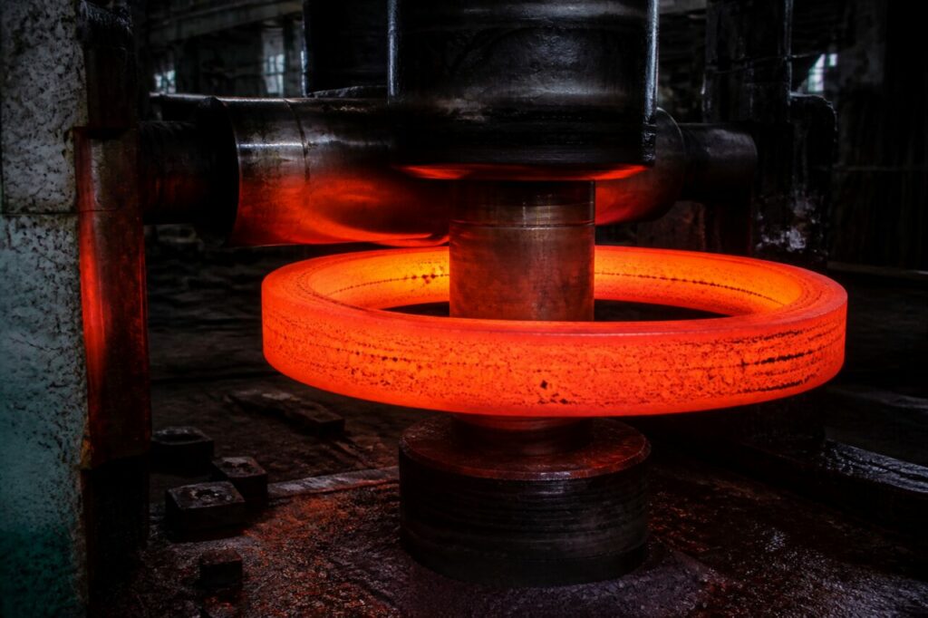 Un anello d’acciaio incandescente ruota grazie alla spinta dei rulli di forgiatura